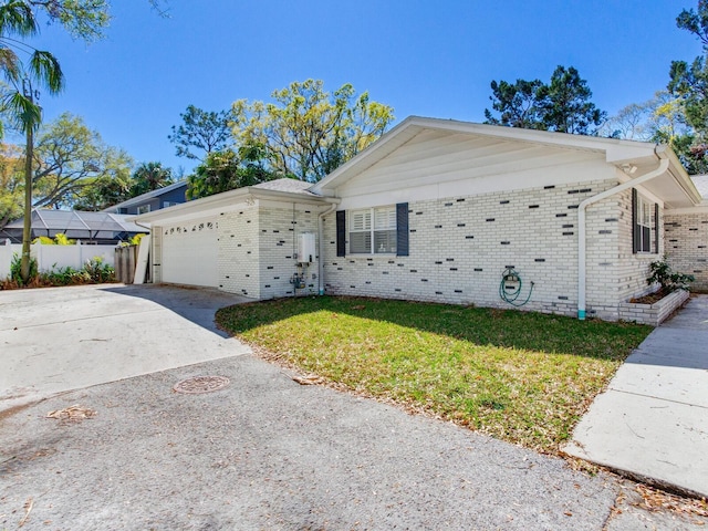 ranch-style house with brick siding, a front lawn, fence, concrete driveway, and a garage