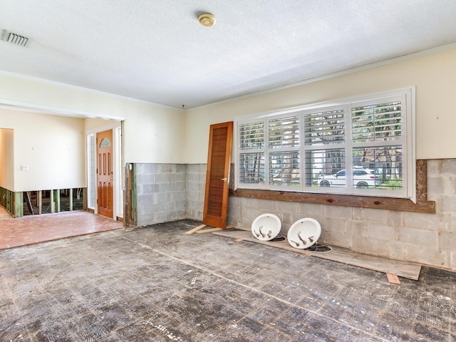 unfurnished room featuring ornamental molding, visible vents, and a textured ceiling