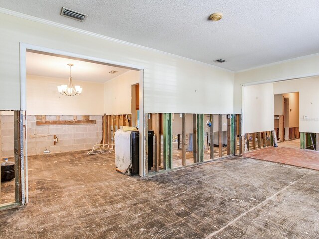 empty room featuring visible vents, a textured ceiling, an inviting chandelier, and crown molding