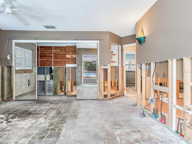 interior space with visible vents, a textured ceiling, and a ceiling fan