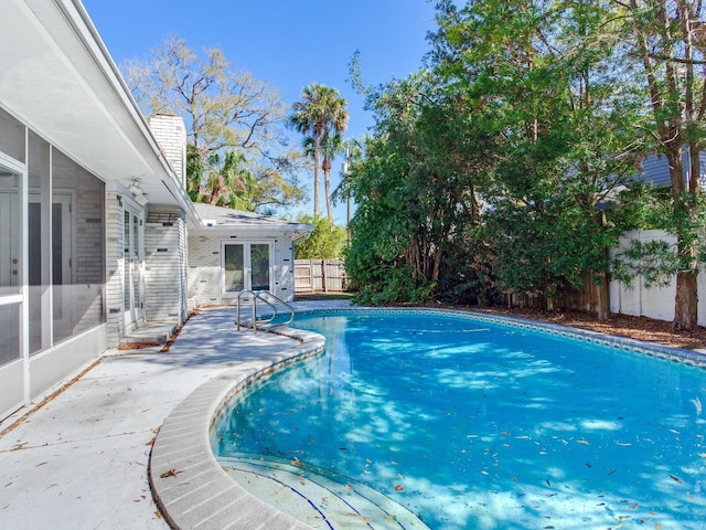 view of swimming pool featuring a patio, a fenced in pool, a fenced backyard, a sunroom, and french doors