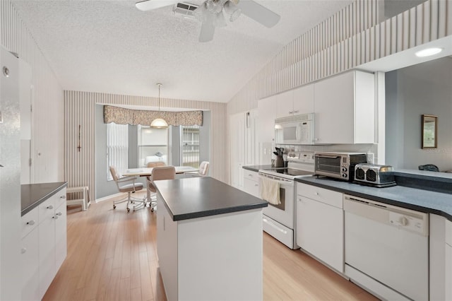 kitchen featuring dark countertops, visible vents, and white appliances