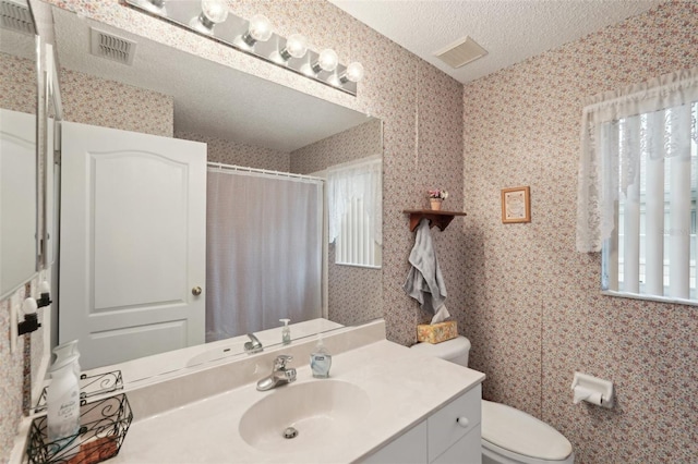 bathroom with visible vents, toilet, wallpapered walls, and a textured ceiling