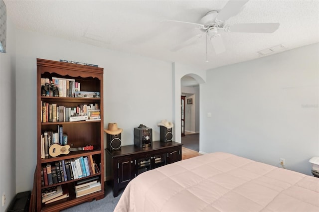 bedroom featuring visible vents, arched walkways, a textured ceiling, and ceiling fan