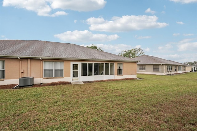 back of property featuring central AC unit, stucco siding, and a yard