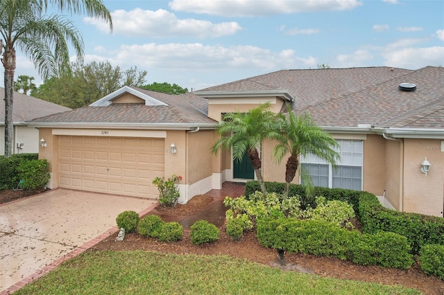 ranch-style home featuring stucco siding, roof with shingles, concrete driveway, and an attached garage