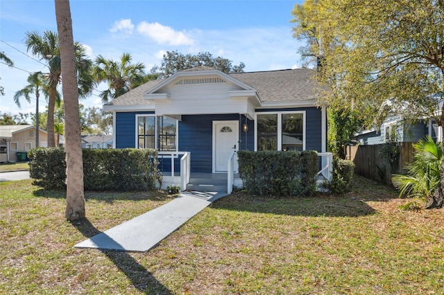 bungalow featuring a porch, a front yard, fence, and a shingled roof