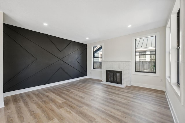 unfurnished living room featuring recessed lighting, a brick fireplace, baseboards, and light wood finished floors