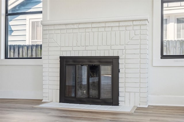 interior details with a brick fireplace, baseboards, and wood finished floors