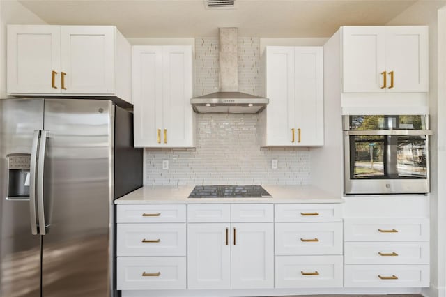 kitchen with white cabinets, wall chimney exhaust hood, appliances with stainless steel finishes, light countertops, and backsplash