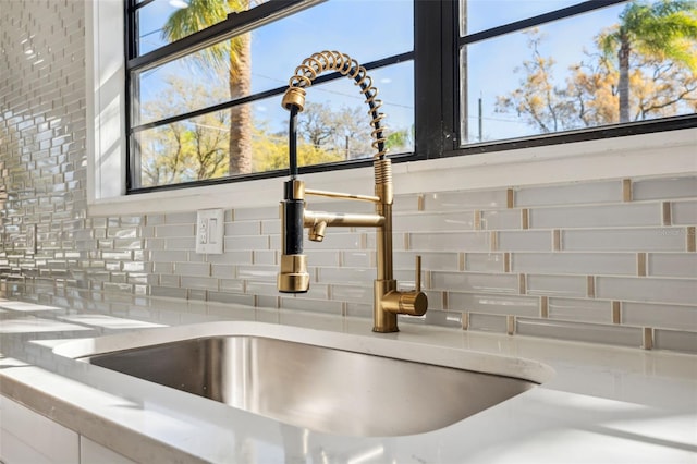 details with white cabinetry, a sink, and backsplash