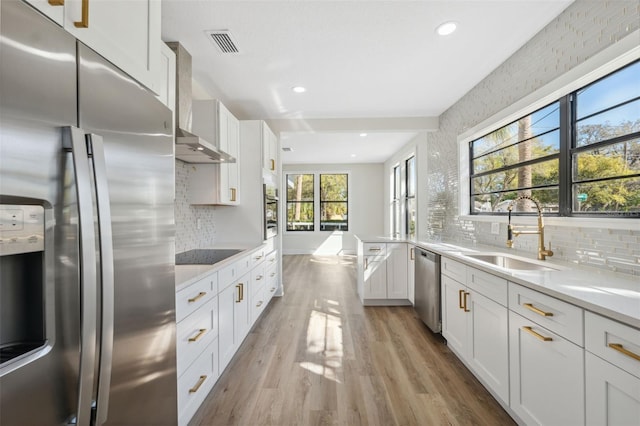 kitchen with visible vents, light wood-style flooring, stainless steel appliances, light countertops, and a sink