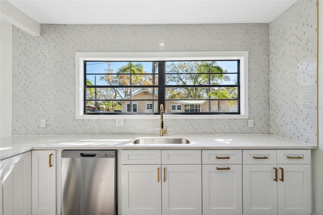 kitchen featuring light countertops, decorative backsplash, white cabinets, a sink, and dishwasher