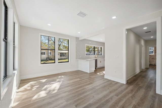 unfurnished living room featuring light wood-style floors, baseboards, visible vents, and recessed lighting