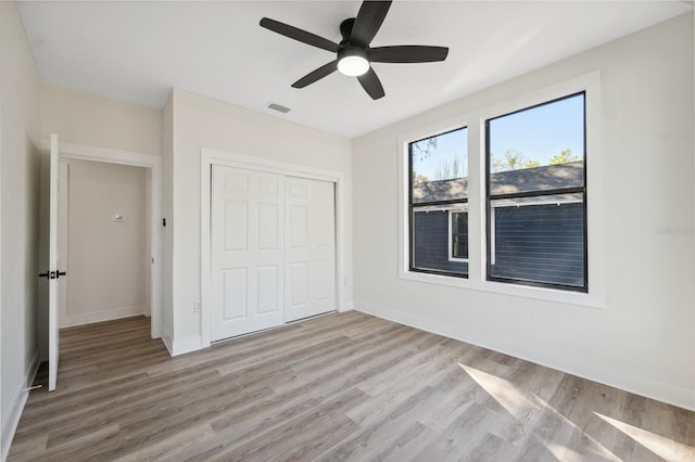 unfurnished bedroom with light wood-type flooring, a closet, visible vents, and baseboards