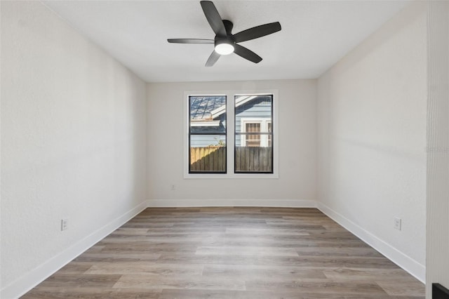 spare room with light wood finished floors, baseboards, and a ceiling fan