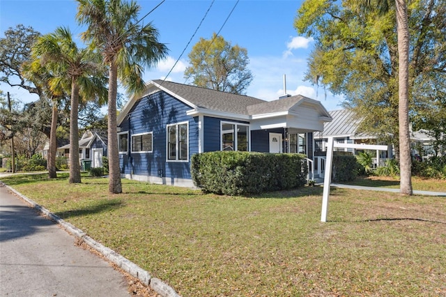 bungalow featuring a front lawn and roof with shingles