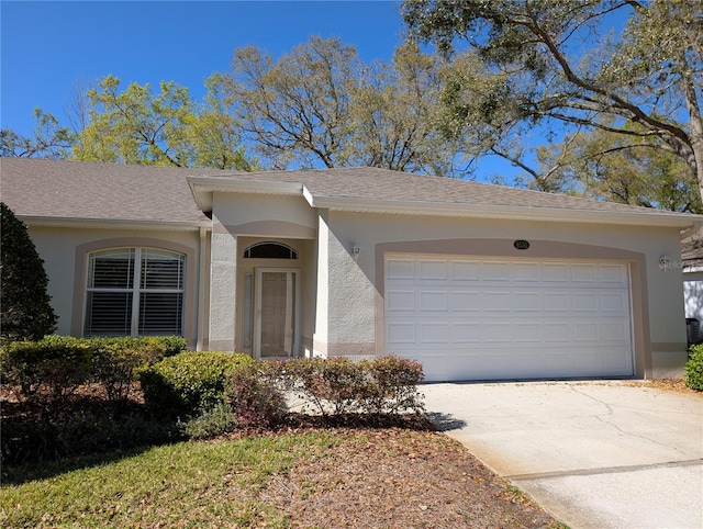 ranch-style house featuring a garage, concrete driveway, roof with shingles, and stucco siding