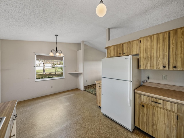 kitchen featuring a notable chandelier, light countertops, freestanding refrigerator, vaulted ceiling, and a textured ceiling