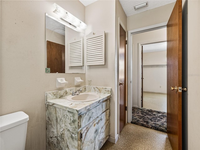 bathroom with toilet, a textured ceiling, vanity, and visible vents