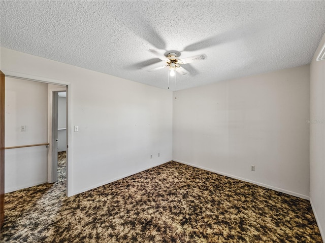 carpeted spare room with ceiling fan, baseboards, and a textured ceiling