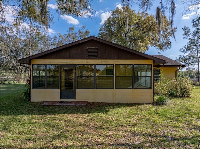 back of house with a sunroom and a lawn