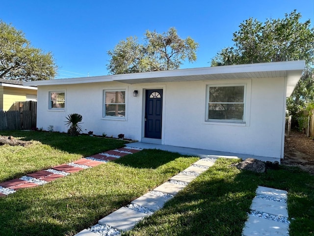 ranch-style home featuring a front yard, fence, and stucco siding