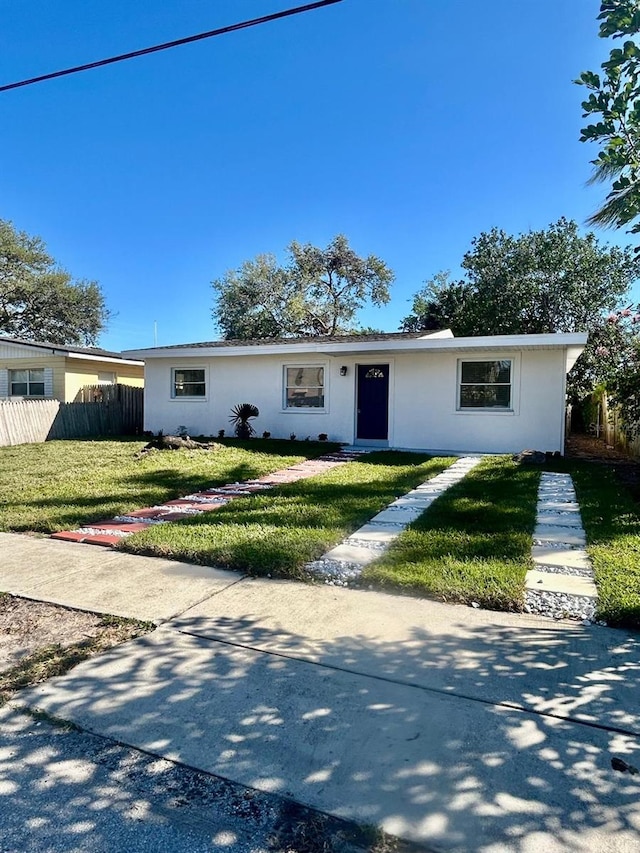 ranch-style home with a front yard, fence, and stucco siding