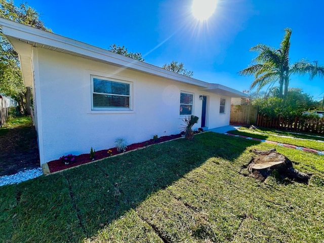 ranch-style house with stucco siding, fence, and a front yard