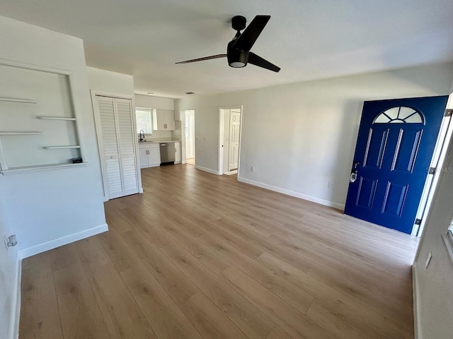 unfurnished living room with a sink, ceiling fan, baseboards, and wood finished floors