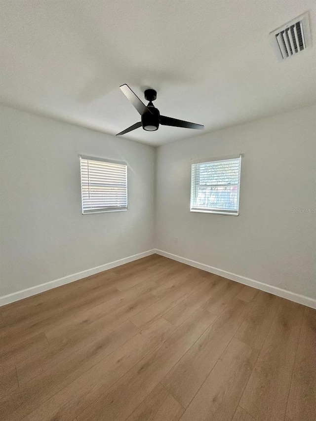 unfurnished room with a ceiling fan, baseboards, visible vents, and wood finished floors