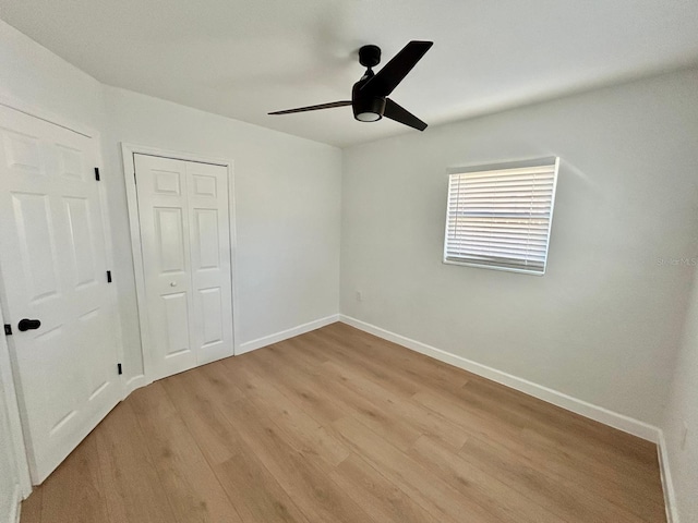 unfurnished bedroom with light wood-type flooring, a closet, ceiling fan, and baseboards