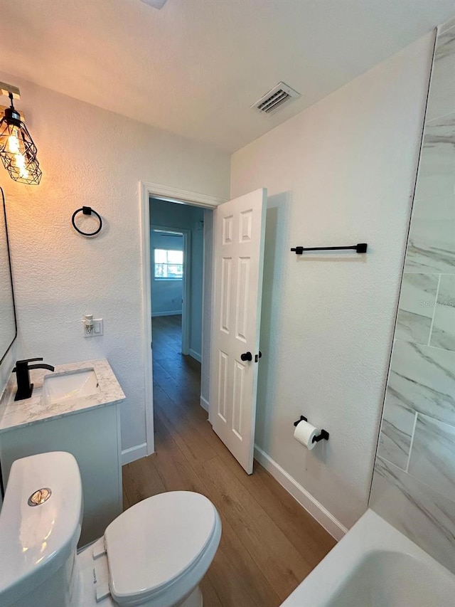 full bathroom with a washtub, baseboards, visible vents, and toilet