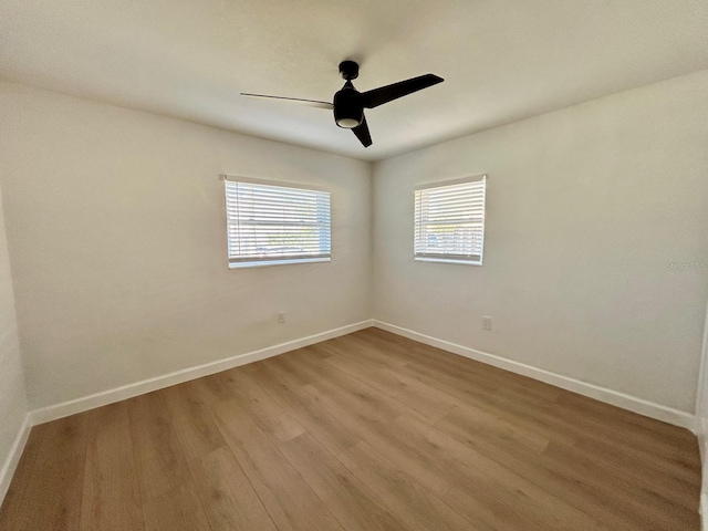 empty room with ceiling fan, baseboards, and wood finished floors