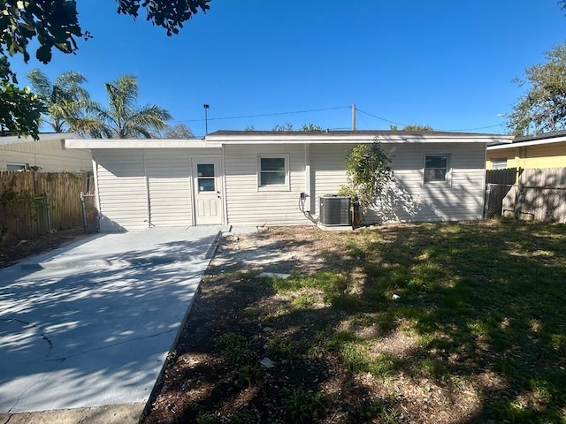 back of property with cooling unit, fence, and a lawn