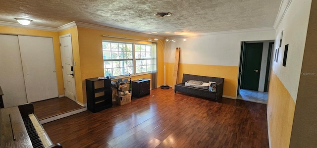 interior space featuring dark wood-type flooring, visible vents, crown molding, and a textured ceiling