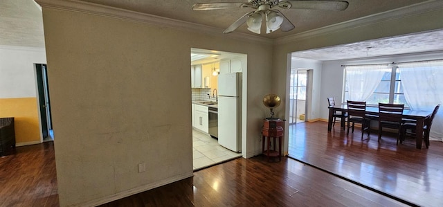 dining room with crown molding, ceiling fan, a textured ceiling, wood finished floors, and baseboards