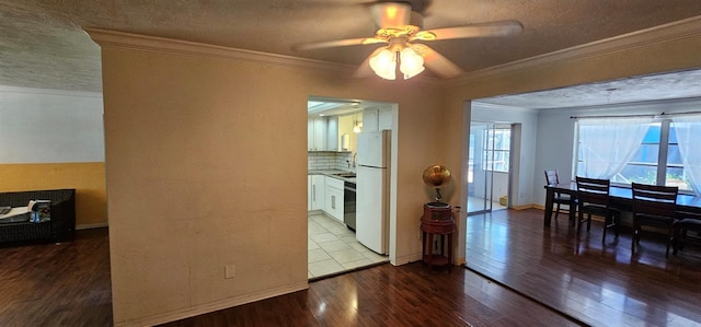 dining room with a textured ceiling, baseboards, wood finished floors, and crown molding