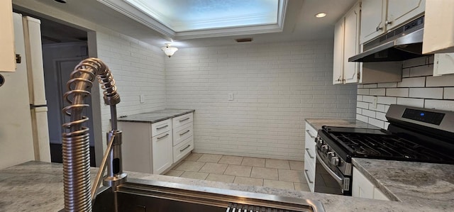 kitchen featuring light tile patterned flooring, under cabinet range hood, white cabinets, stainless steel range with gas stovetop, and crown molding