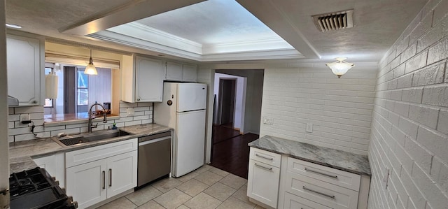 kitchen featuring tasteful backsplash, visible vents, stainless steel dishwasher, freestanding refrigerator, and a sink