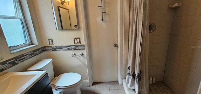 full bathroom featuring toilet, tile patterned flooring, a tile shower, and vanity