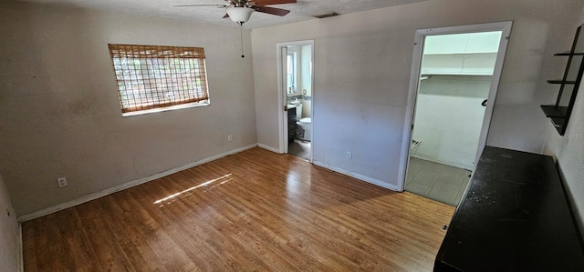 unfurnished bedroom with a walk in closet, a closet, visible vents, wood finished floors, and baseboards