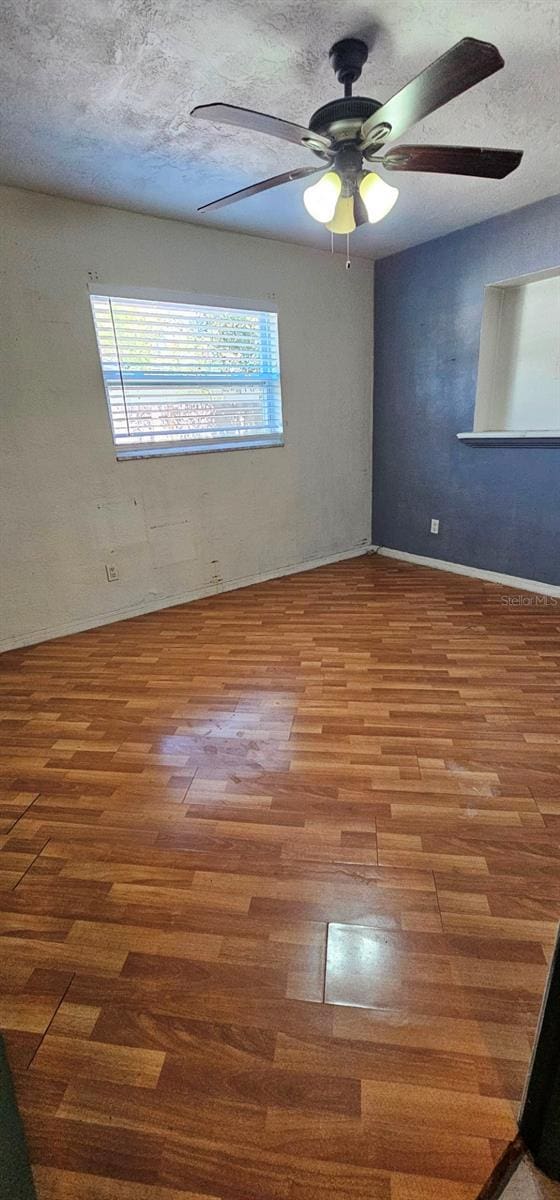 empty room featuring ceiling fan, a textured ceiling, and wood finished floors