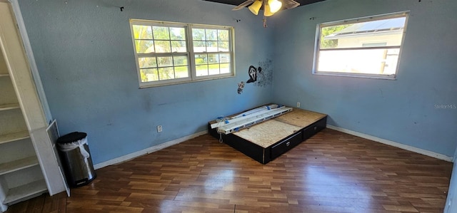 unfurnished bedroom with multiple windows, wood finished floors, and baseboards