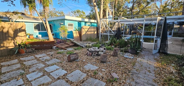 view of yard with glass enclosure and fence