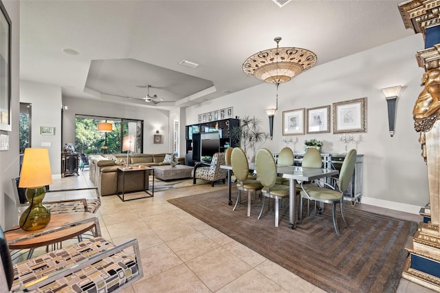 dining space with light tile patterned floors, a tray ceiling, baseboards, and visible vents