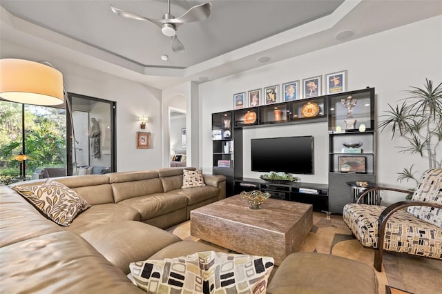 living room featuring a tray ceiling and a ceiling fan