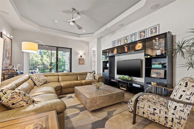 living room with a tray ceiling and ceiling fan