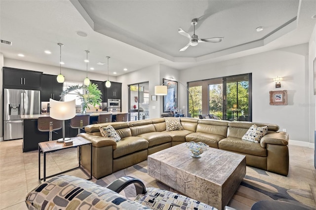 living room with visible vents, a tray ceiling, light tile patterned flooring, recessed lighting, and ceiling fan