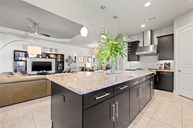 kitchen with light tile patterned floors, visible vents, a kitchen island, and wall chimney range hood